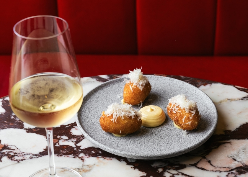 Crispy cheese croquettes with creamy sauce and a glass of white wine at Bistrot at Wild Honey